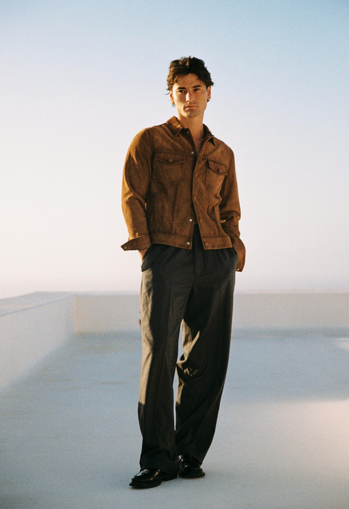 Man in a brown jacket standing on a rooftop