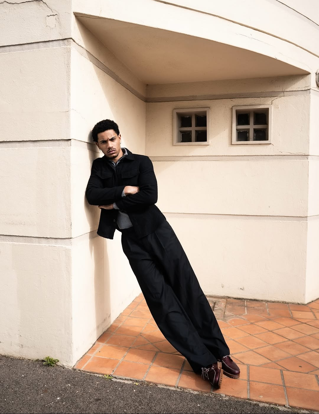 Man in a black jacket leaning against a wall