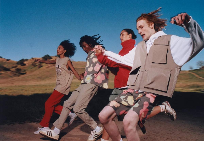 Four friends in Dockers clothing running hand in hand across a sunny hillside